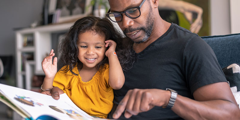 Diabetes och Försäkrings livförsäkring – pappa läser en bok för sin dotter